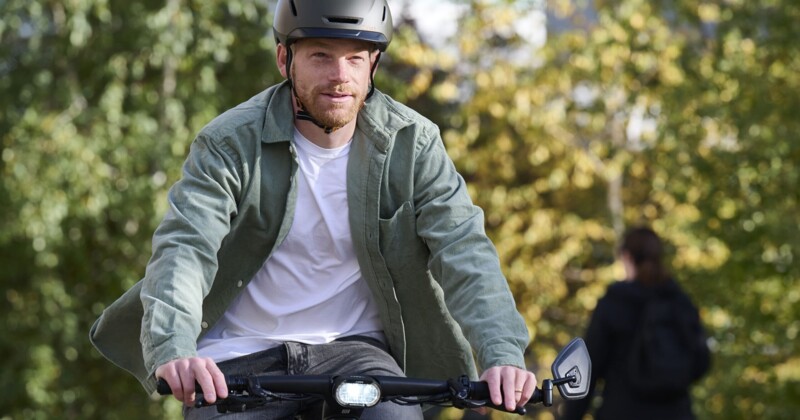 Ein Mann mit Helm fährt auf einem Fahrrad durch eine grüne Umgebung, während er nach vorne schaut.