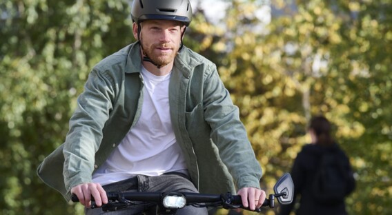 Ein Mann mit Helm fährt auf einem Fahrrad durch eine grüne Umgebung, während er nach vorne schaut.